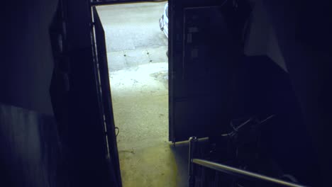 hand hold still view of interior stair gate way with downstairs open door and grunge dirty concrete ground look out to outside street with metal mail box of ghetto old dirty asia apartment building