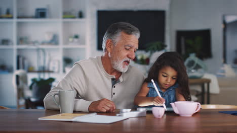 Senior-Hispanic-man-talks-with-his-granddaughter-while-she-uses-stylus-and-tablet-computer,-close-up