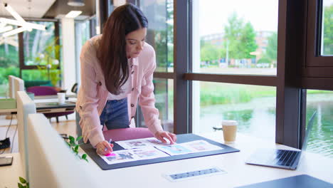 Mujer-De-Negocios-Parada-Frente-Al-Escritorio-En-La-Oficina-Aprobando-O-Revisando-Pruebas-O-Diseños-De-Diseño.