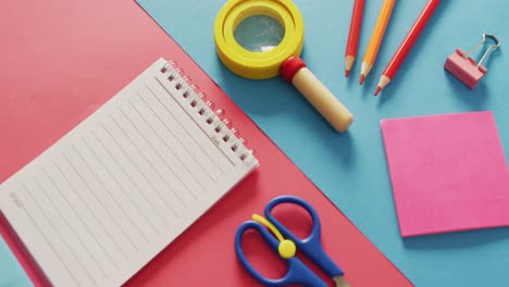 video of composition of school items with notebook with copy space on pink and blue surface