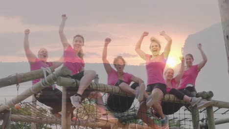 animation of sunset over diverse women at obstacle course raising hands