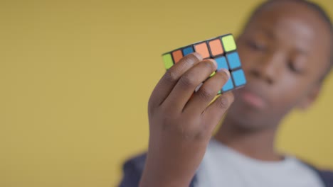 retrato de estudio de un niño en el espectro asd resolviendo un cubo de rompecabezas sobre fondo amarillo 4