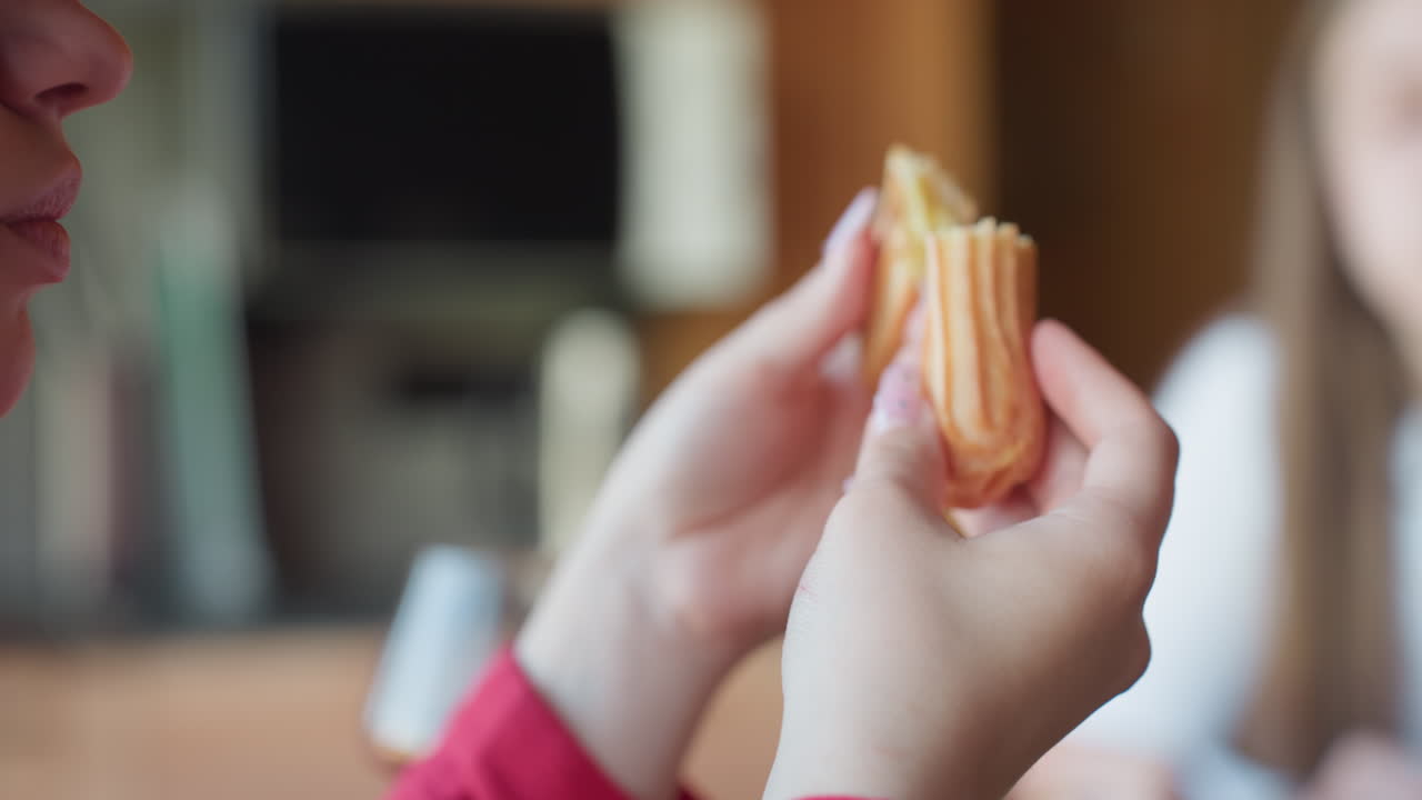 Close up of glass kettle with hot herbal infusion, steam forming on surface as women sit around wooden table in background, soft lighting creates peaceful warm indoor atmosphere