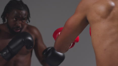 close up studio shot of two male boxers wearing gloves fighting in boxing match against grey background 5