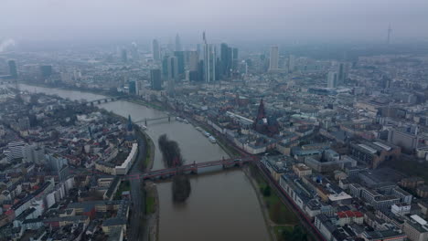 Hochwinkelansicht-Des-Gebäudes-In-Einem-Städtischen-Stadtteil-Entlang-Des-Flusses.-Kippen-Sie-Nach-Oben,-Um-Ein-Dunstiges-Stadtbild-Mit-Wolkenkratzern-In-Der-Innenstadt-Zu-Enthüllen.-Frankfurt-Am-Main,-Deutschland