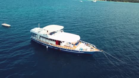 Drone panning around a white boat on the blue sea in the Indian Ocean, Maldives