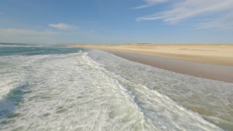 Drone-flying-low-over-ocean-water-surface-with-surfer-paddling-on-surfboards-waiting-for-waves,-Soustons-in-France