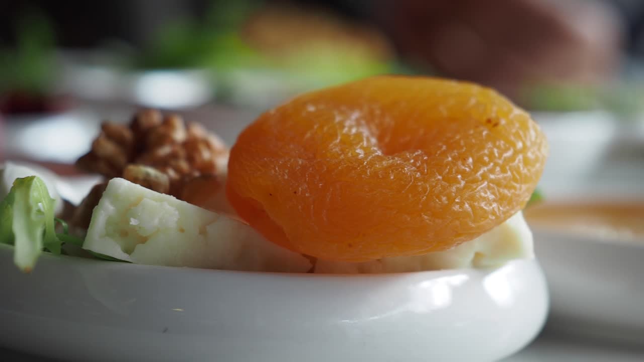 Albicocche secche, noci e formaggio su un piatto bianco
