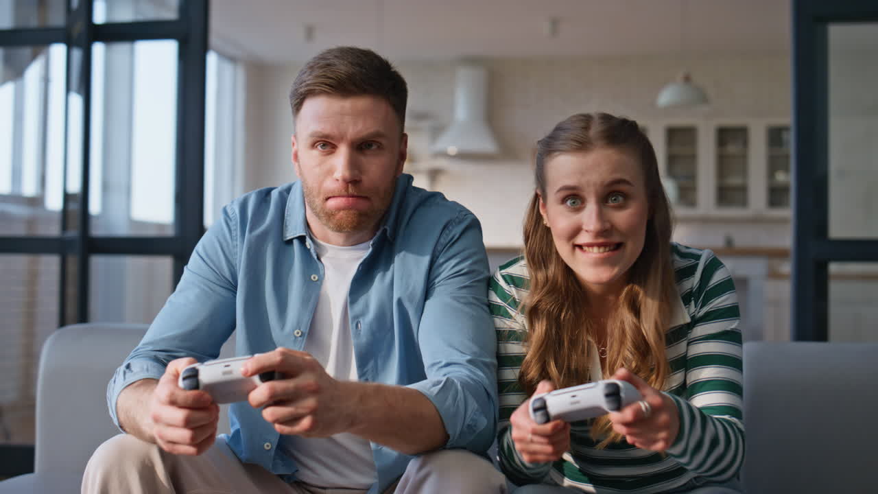 Giocatori di video che vincono il gioco seduti sul divano con la console a casa moderna in primo piano