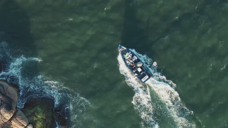 aerial top view of fishing boat sailing coastline of barra da lagoa canal, santa catarina, florianópolis, brazil