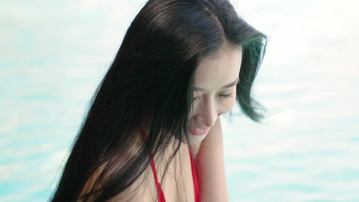 Donna sorridente in bikini rosso a bordo acqua