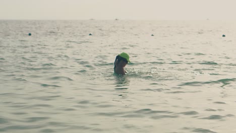 mother plays with little girl in water of calm ocean