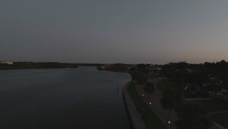 an aerial view of clear creek and the boardwalk with illuminated palm trees along upper bay road at dusk in nassau bay, texas.