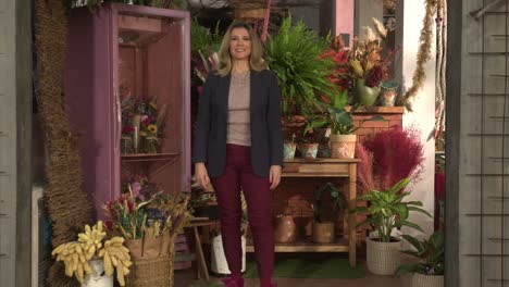 la dueña de la tienda de flores de pie frente a la tienda de negocios local sonriendo retrato