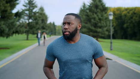 athlete doing cardio workout on asphalt road. bearded runner training outdoors