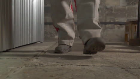 worker in protective pants walks along empty plant workshop