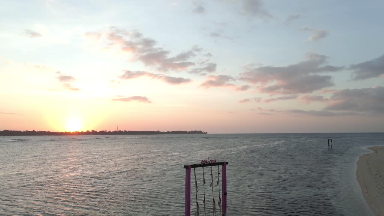 배경에서 일몰 동안 물 속에서 사랑 그네를 들고 모래 해변을 걷고 있는 소녀