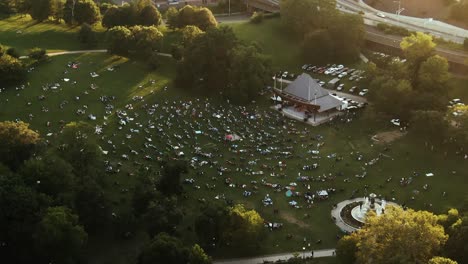 people sitting on grass field in bushnell park enjoying show, hartford