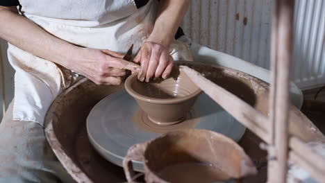 close up of male potter shaping clay for bowl on pottery wheel in ceramics studio