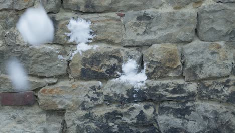 close-up en cámara lenta de bolas de nieve golpeando y salpicando una pared de piedra gris
