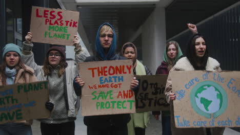 multicultural group of young activists holding cardboard placards protesting against climate change looking at camera 1