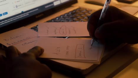 Close-up-view-of-african-left-handed-businessman-writing-in-notebook,-american-male-hands-holding-pen-making-notes