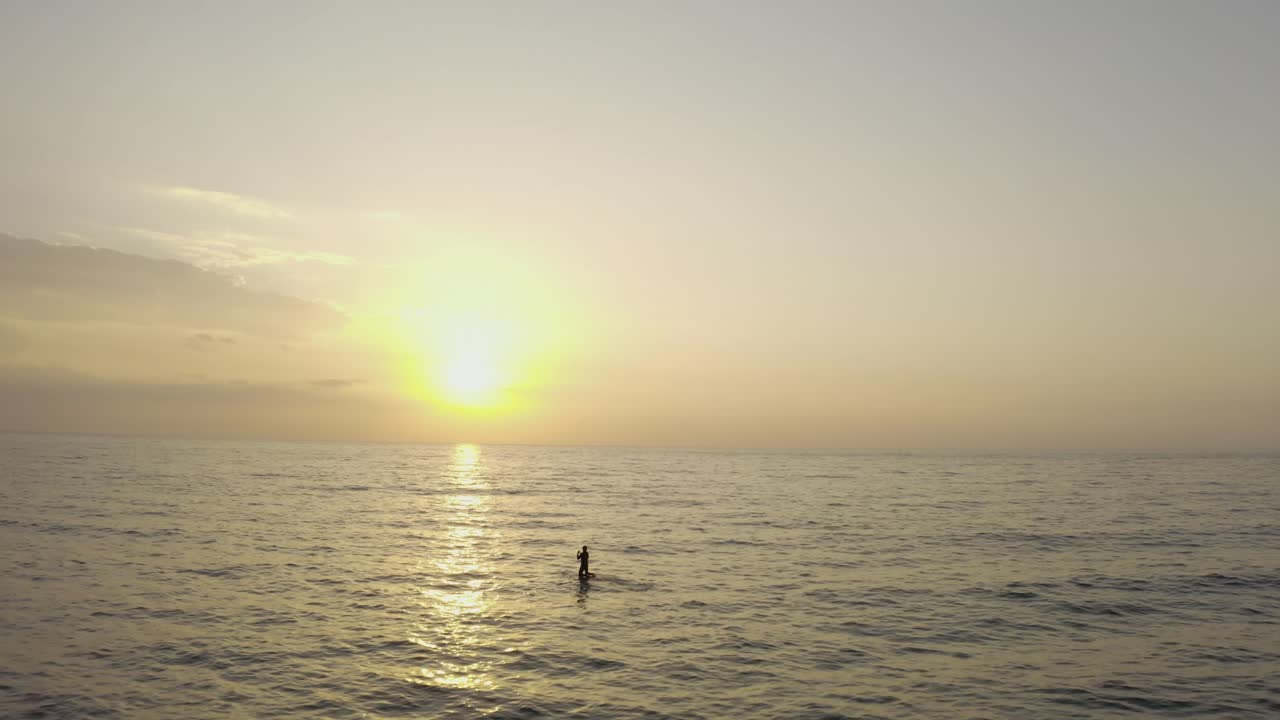 Ripresa aerea 4K - Uomo che fa stand up paddleboard al tramonto - bagliore del sole