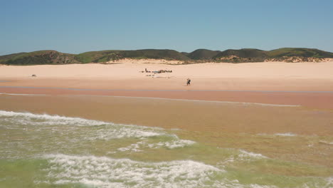 Aerial:-Surfing-the-beach-of-Bordeira-in-the-Algarve,-Portugal