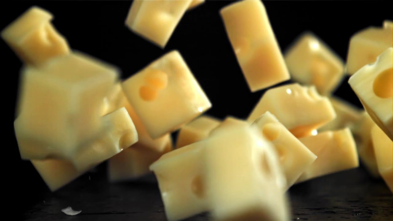 Cubetti di formaggio svizzero che cadono al rallentatore su sfondo nero
