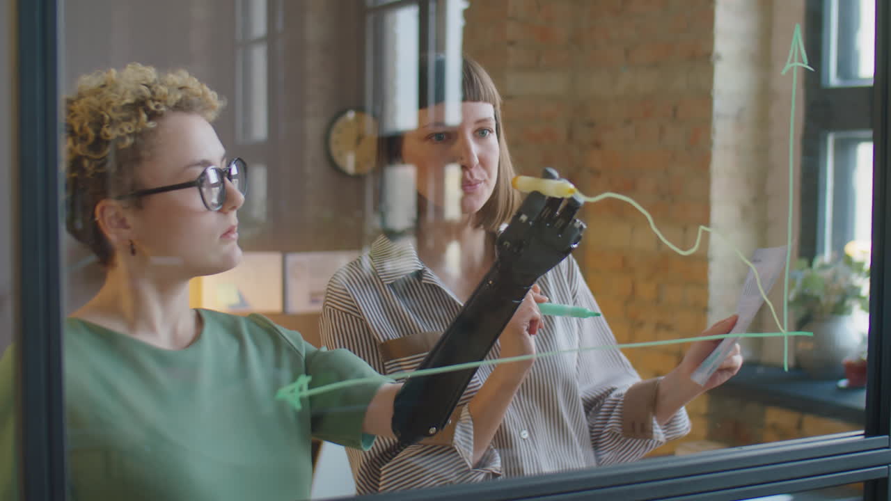 Diverse Businesswomen Discussing Graph on Glass Office Wall