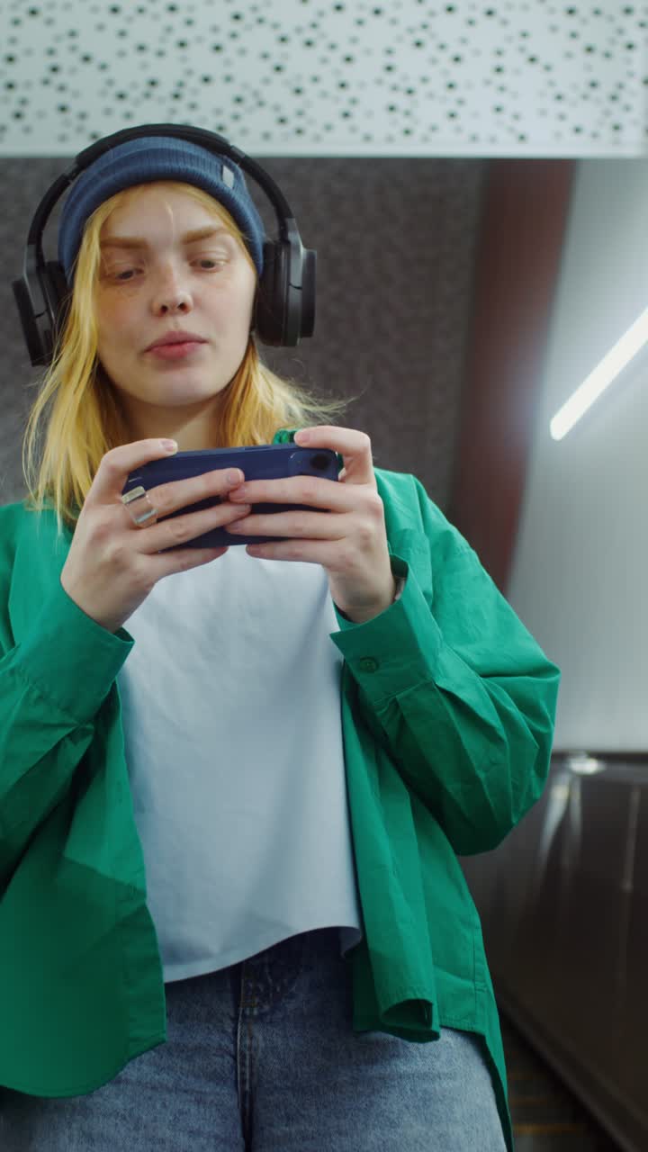 Young woman playing mobile game in metro