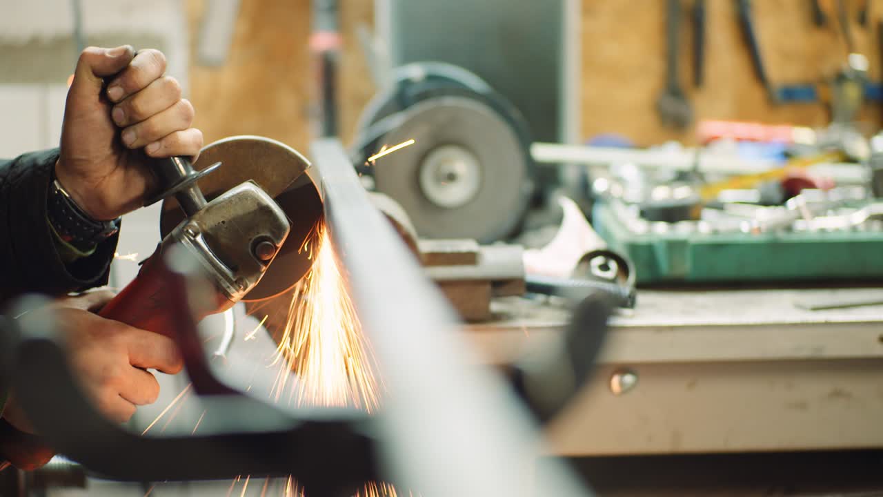 industria del acero - hombre que utiliza un molinillo angular para moler objetos metálicos en el taller.