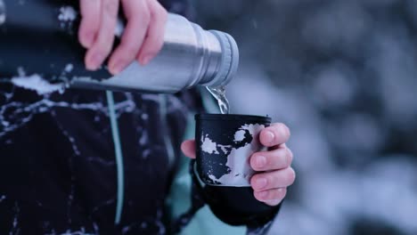 termo vierte té en una taza en medio del frío paisaje invernal