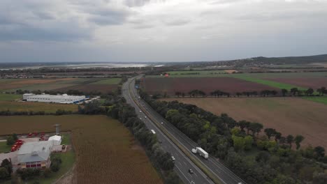 aerial drone reverse showing of busy hungarian highway, beautiful lake in the background