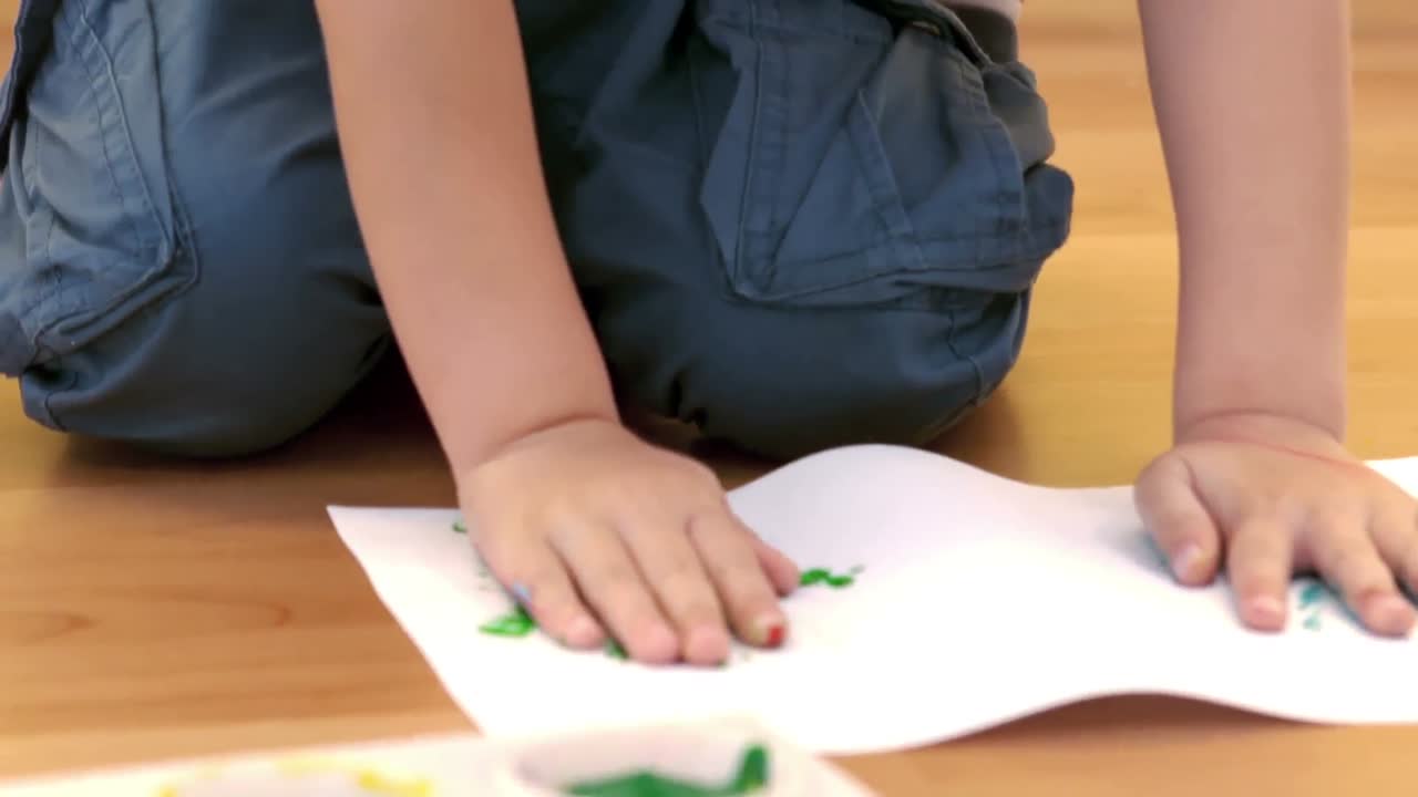 niño usando sus manos para hacer huellas de manos pintadas