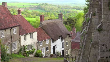 idyllic hillside cottages line a steep cobblestone road in the english countryside