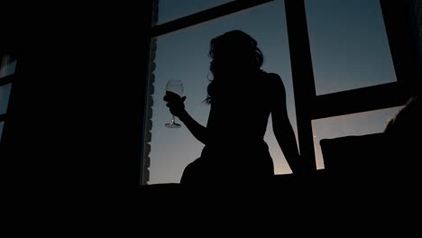 Damensilhouette-Schüttelt-Abends-Wein-Im-Glas-Am-Fenster