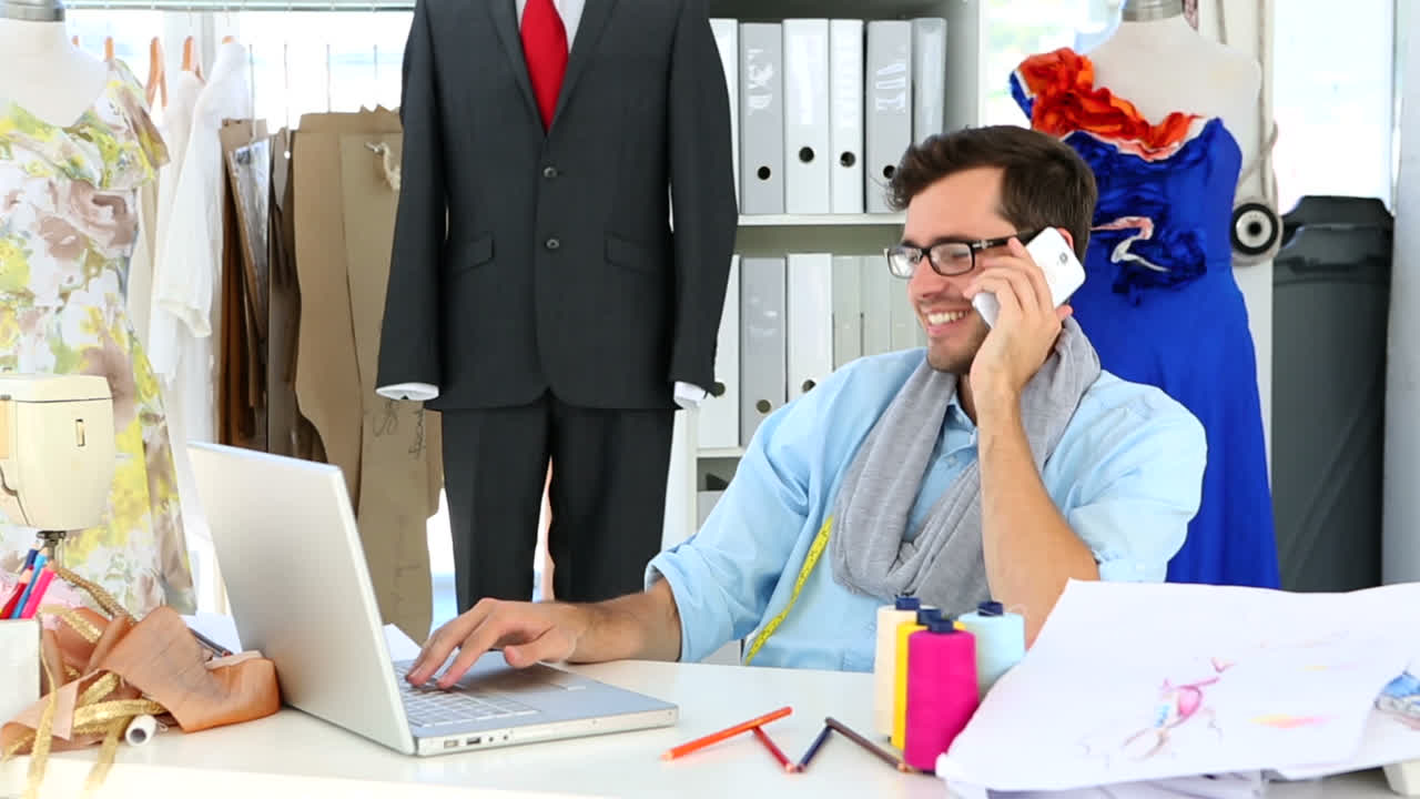 디자이너가 전화로 이야기하고 노트북을 사용하고 있습니다.
