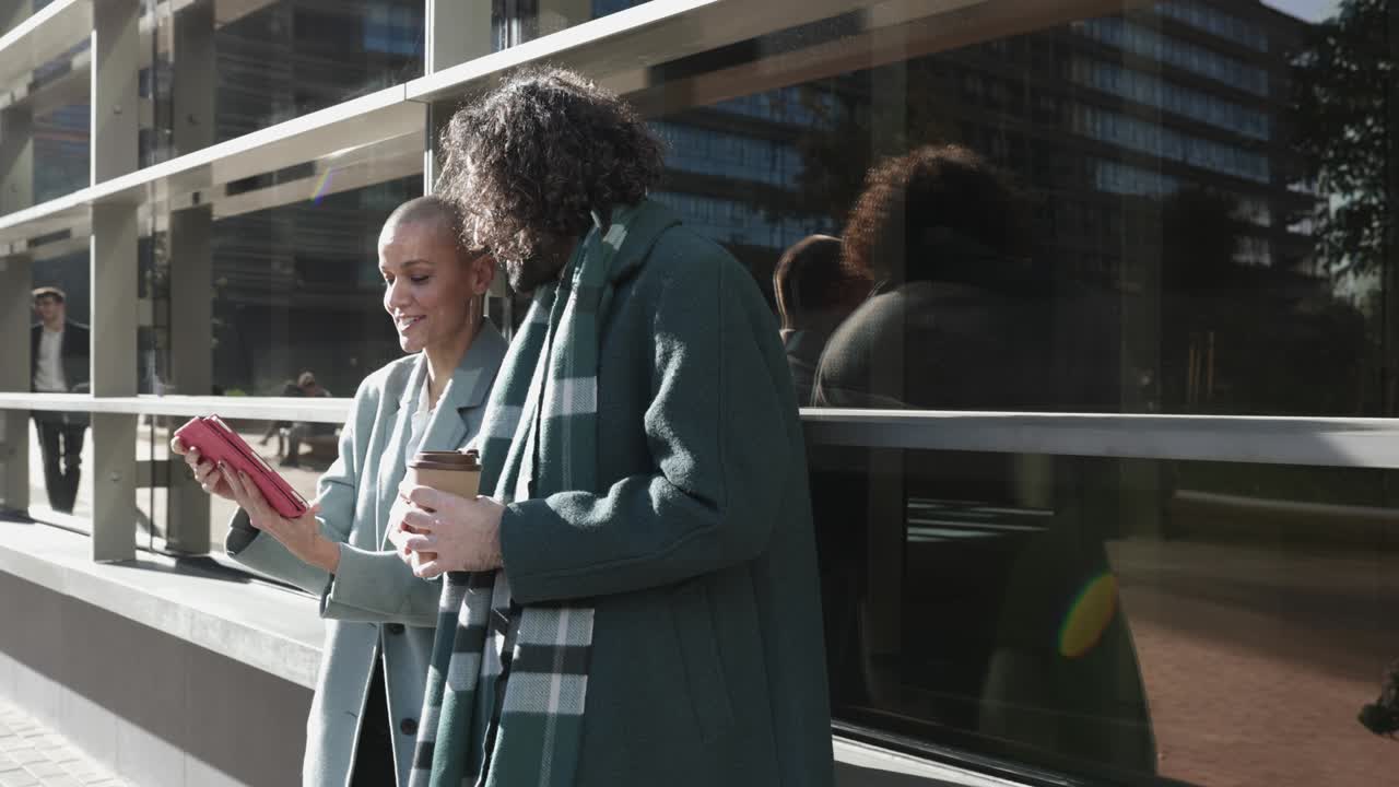 두 명의 젊은 성인 동료들이 디지털 태블릿을 사용하면서 프로젝트에 대해 논의하고 있습니다.