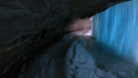 walking narrow path in a cave behind frozen waterfalls in minnesota