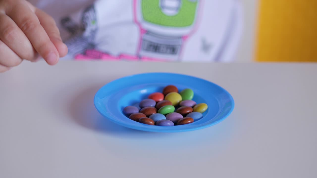 la mano del niño toma dulces de color de un plato