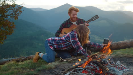 camping tourists enjoy picnic on mountains hike. young couple relax by bonfire.