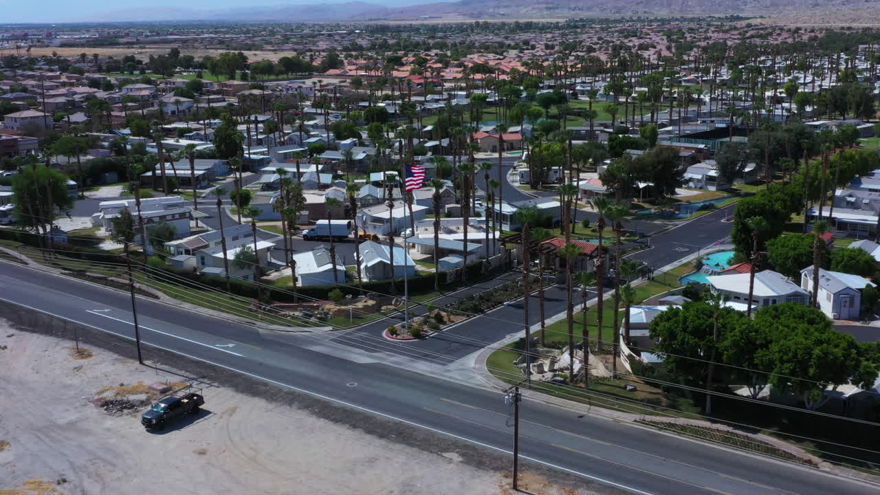미국 국기에 의해 빈 고속도로 위를 비행하고 배경에 산이 있는 평원에 있는 주거용 주택 커뮤니티, covid-19 전염병, 오버헤드 공중 견인