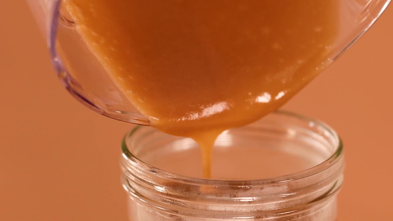 Un denso e cremoso milkshake al cioccolato si versa delicatamente da un frullatore in un barattolo di vetro