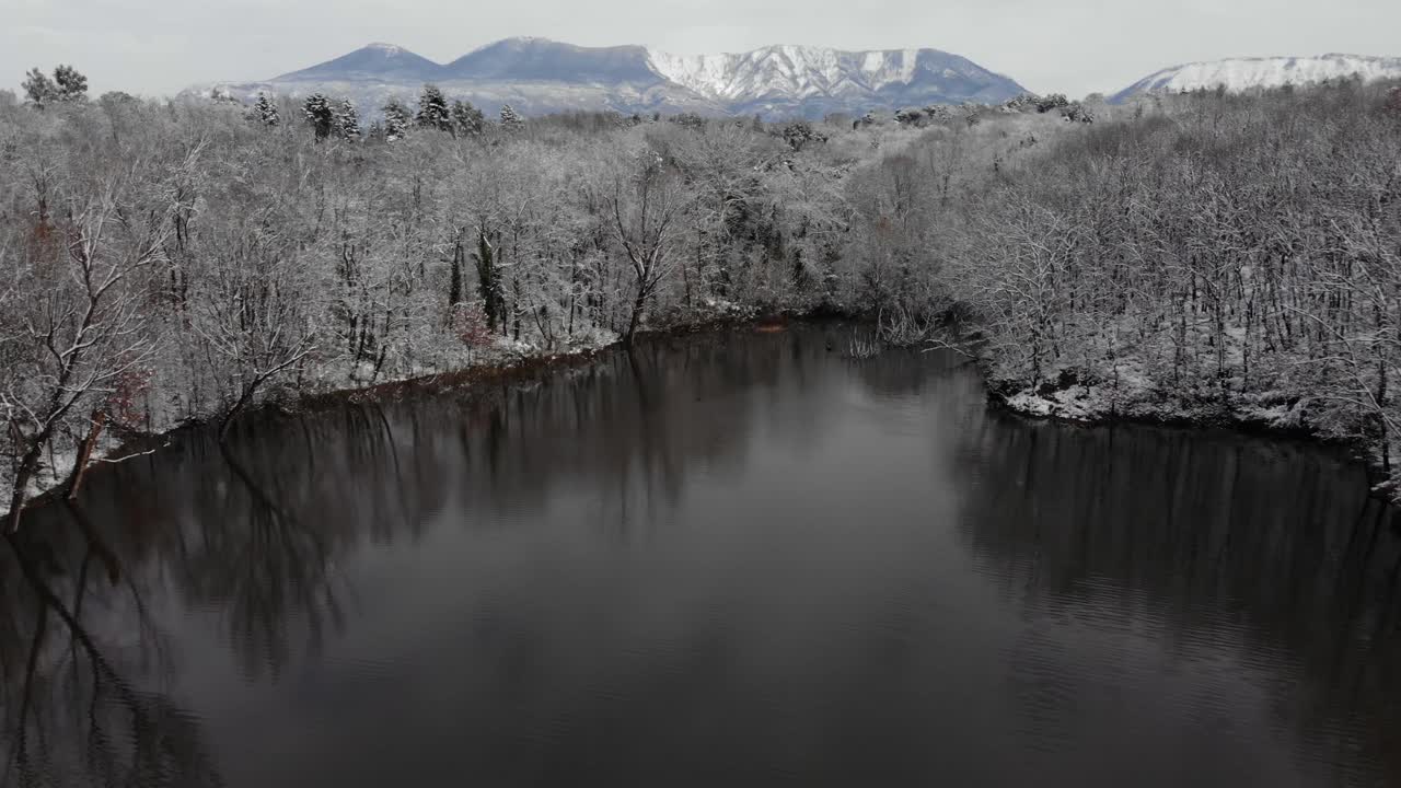 hermoso paisaje nevado en blanco y negro con agua fría del lago que refleja árboles sin hojas