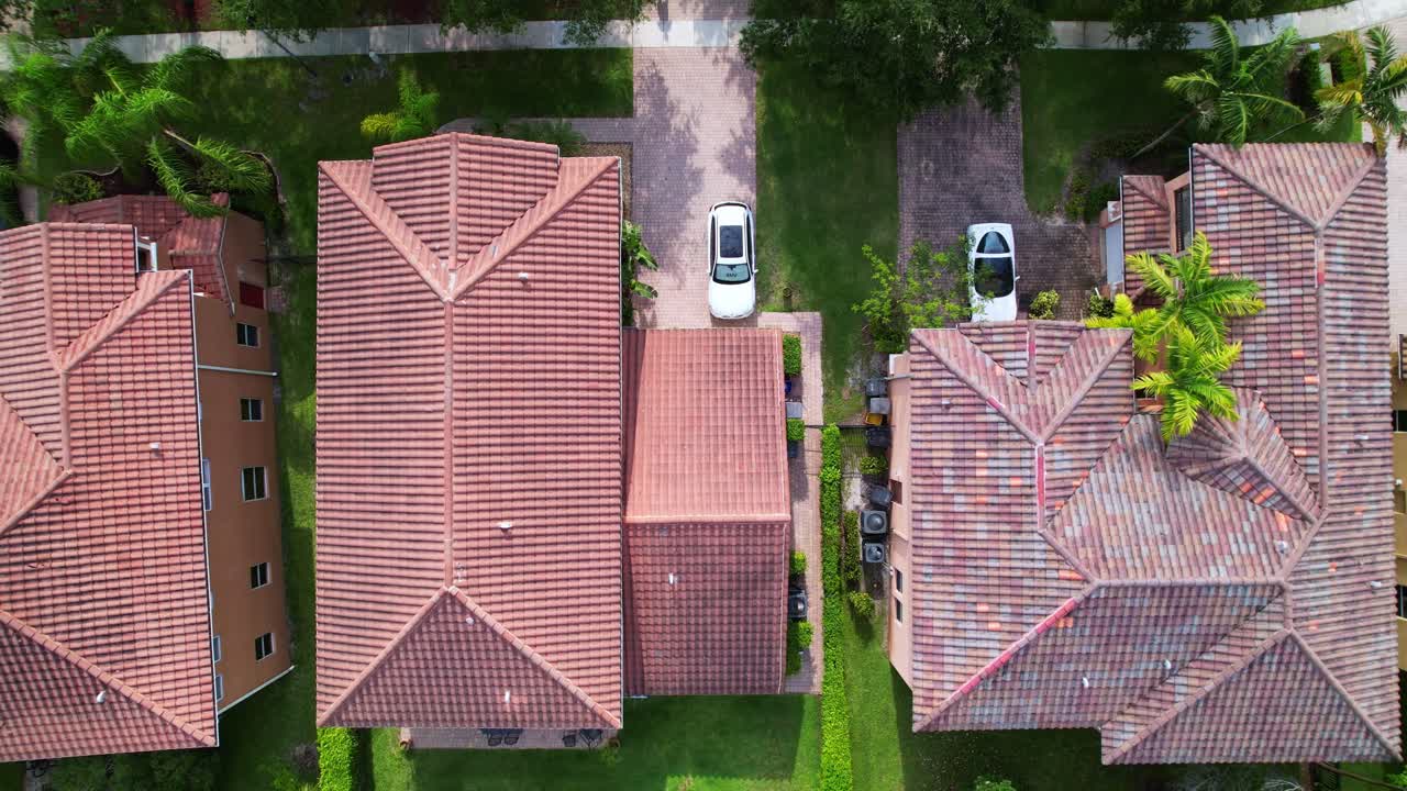 Close up aerial of rooftops with backyards, pools, and surrounding trees