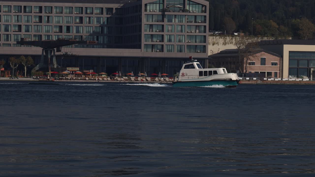 Modern buildings along city waterfront with calm sea and reflections under daylight