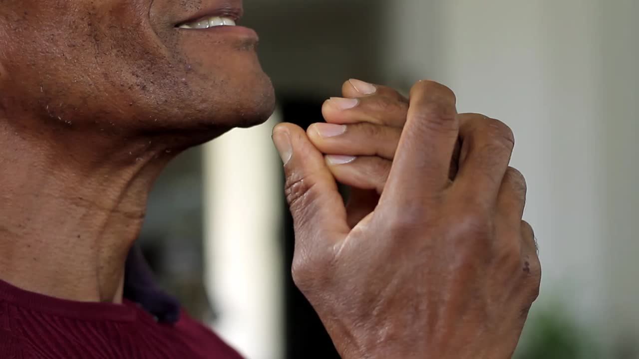 man praying to god with hands together Caribbean man praying with background with people stock footage