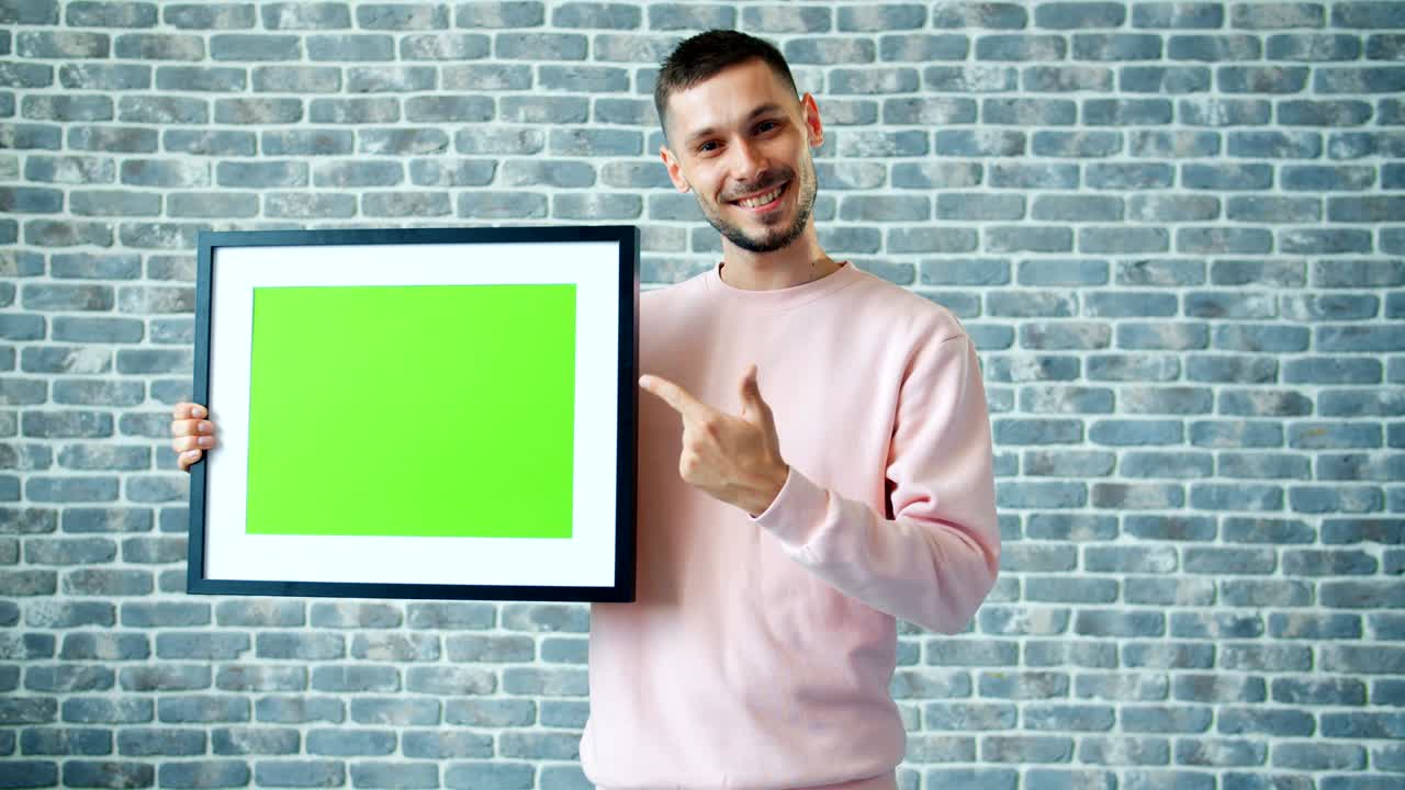 retrato de un hombre guapo sosteniendo el marco de la imagen de la llave de croma y mostrando los pulgares hacia arriba