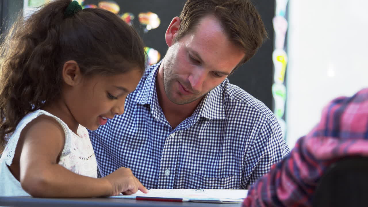 maestro y joven estudiante mirando el cuaderno en clase